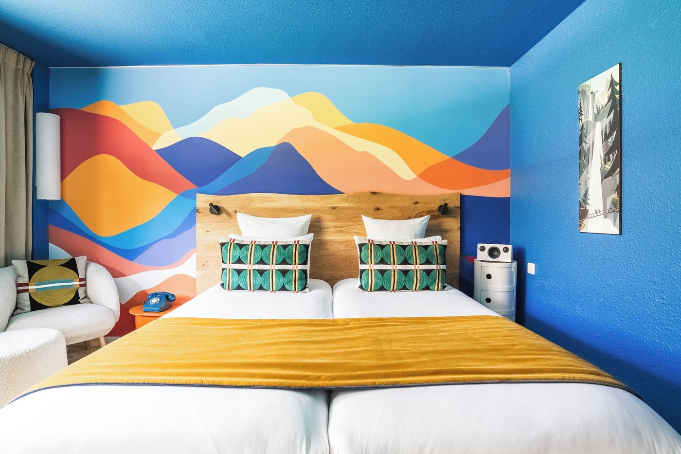 A Big Sky Hotel room with a bed, nightstand, lamp and wall painting.