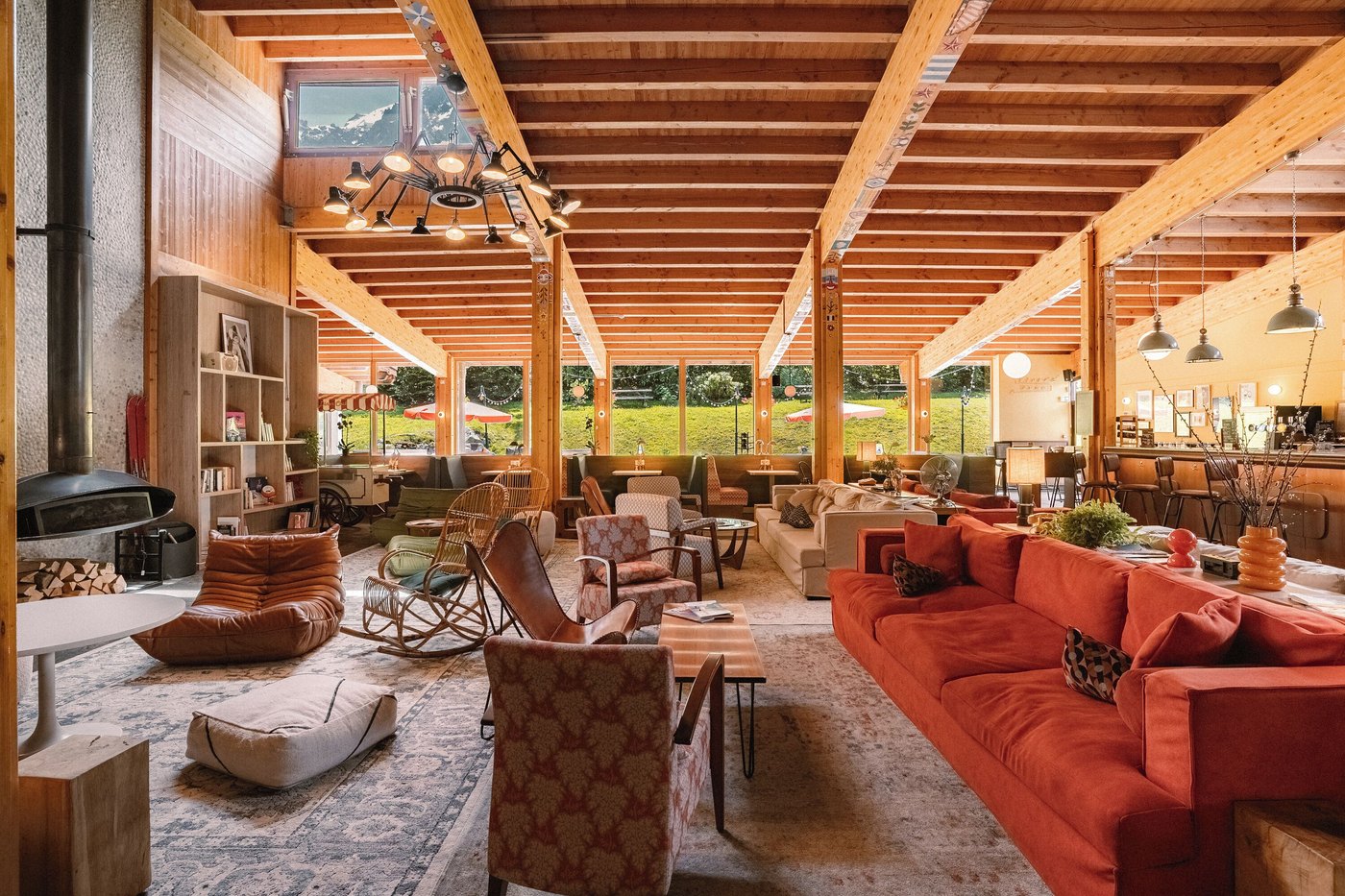 A Big Sky Hotel living area with wooden beams, a fireplace and a large window.