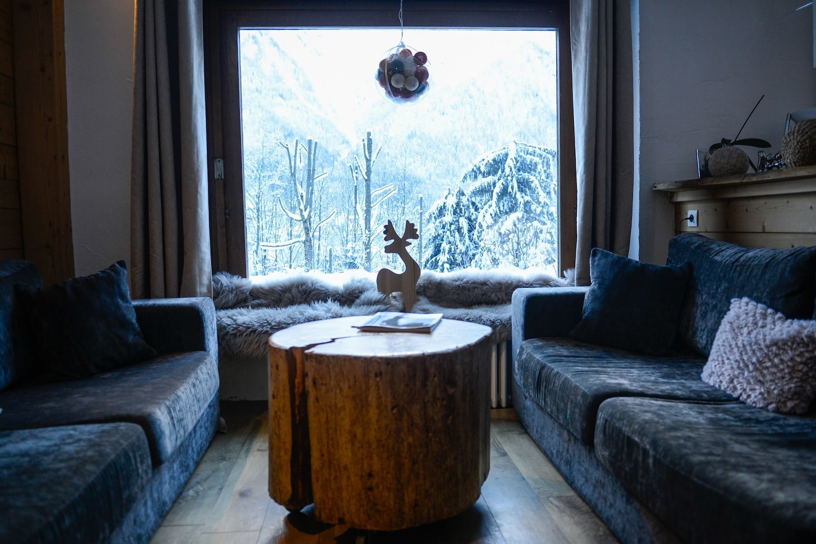 A cozy living room with a large window, a wooden coffee table, and two sofas. - Chalet Hotel Les Campanules (Les Houches)