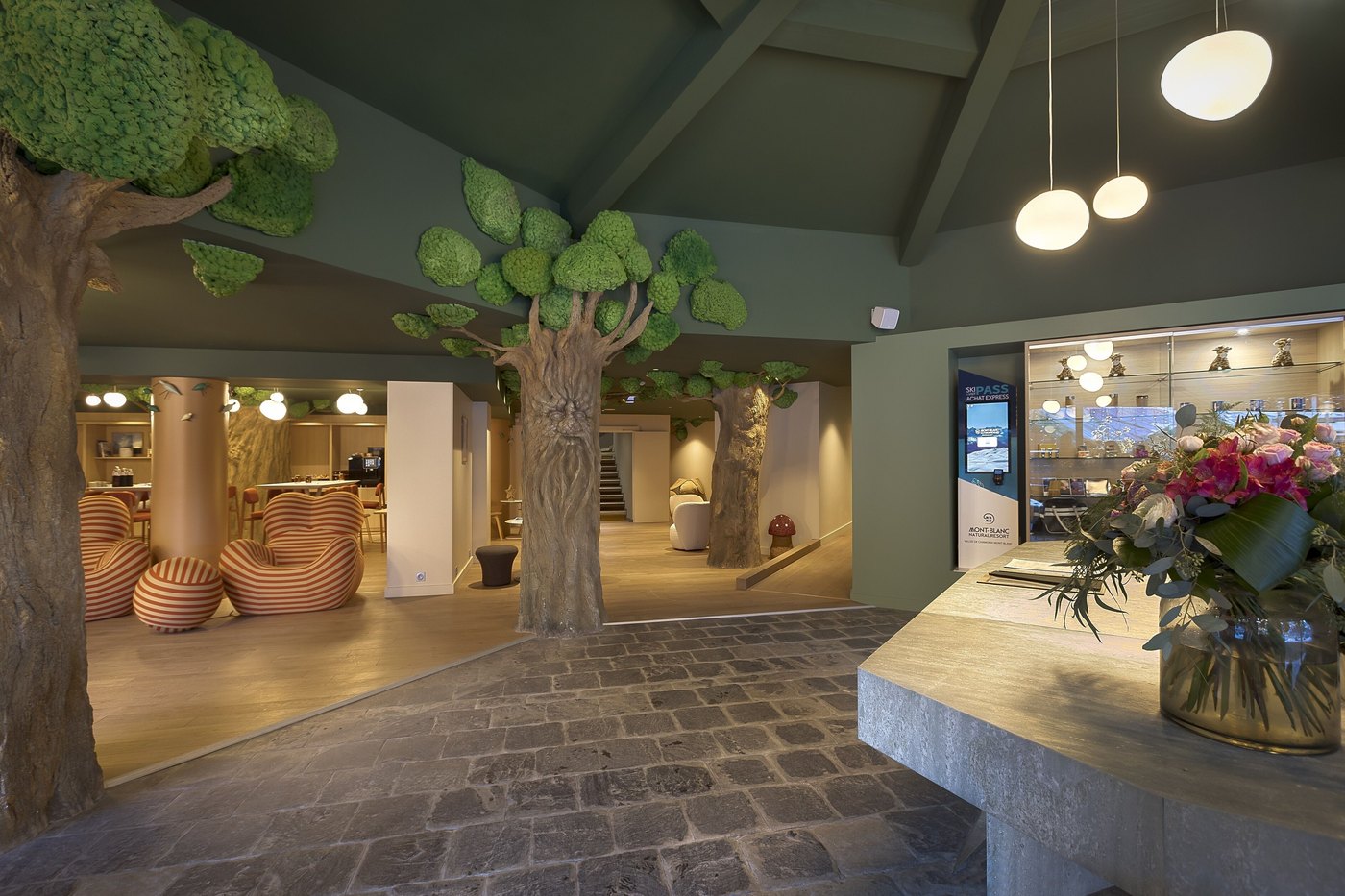 A lobby with a stone floor, a reception desk, and a display of flowers. — Lykke Chamonix